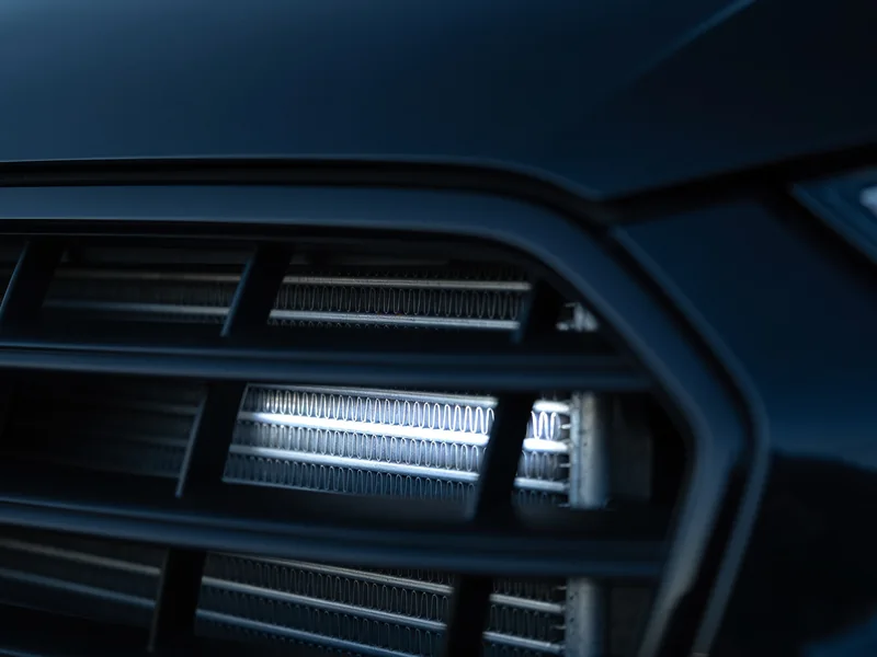 The fins of an AC condenser seen through a car's front grille
