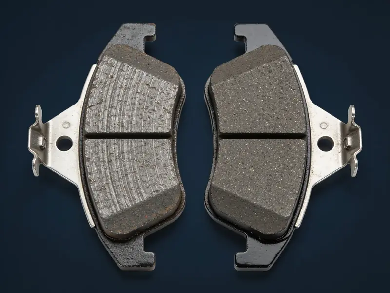 A worn brake pad next to a new brake pad