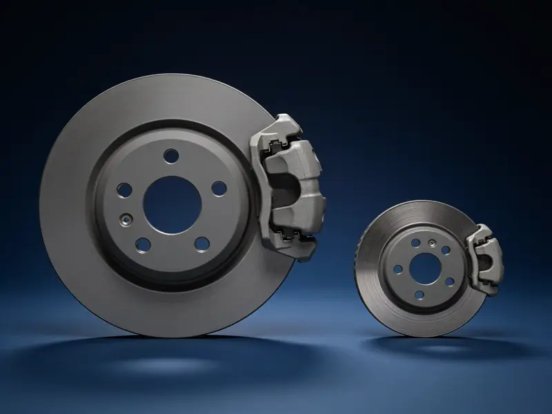 A large brake rotor and caliper next to a much smaller one