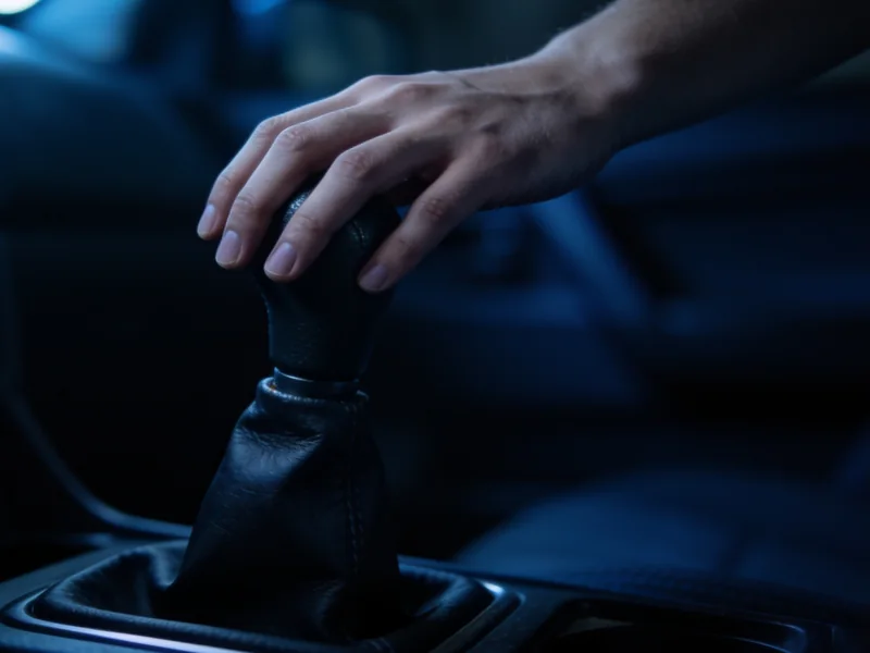 A hand resting on a manual gear shifter