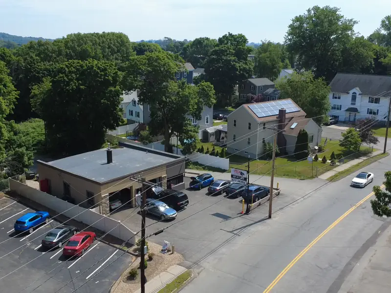 V-Tech Auto Services shop and its parking lot beside a residential street, seen from a drone